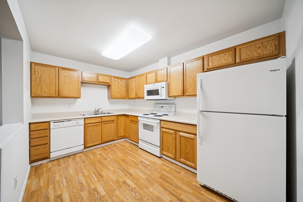 A kitchen with wooden cabinets and white appliances.