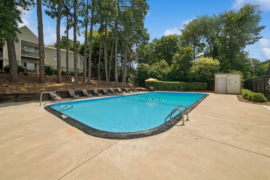 A small pool surrounded by trees and a building.