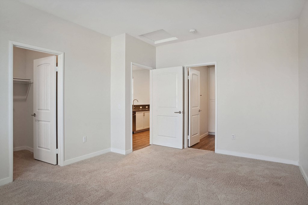 a bedroom with two doors and a carpeted floor at Arrive at Rancho Belago, Moreno Valley