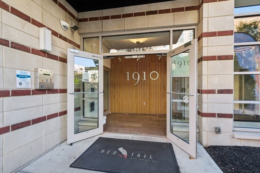 the entrance to a building with an open door and a rug in front of it