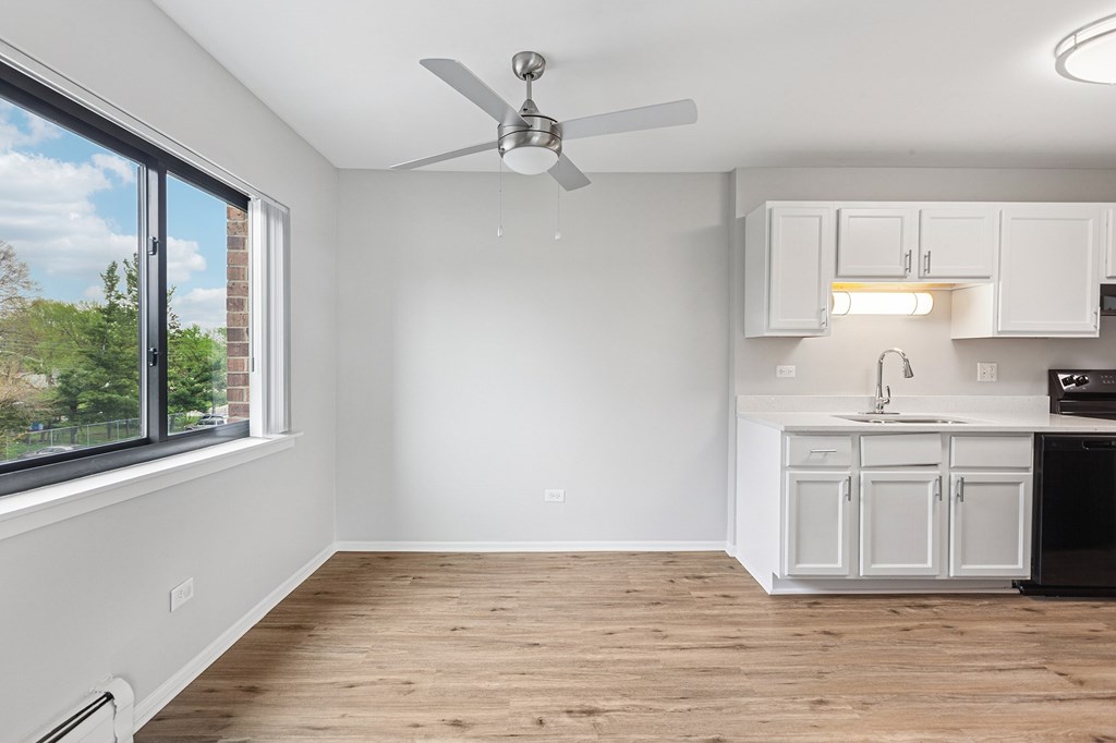 A kitchen with white cabinets and a ceiling fan.