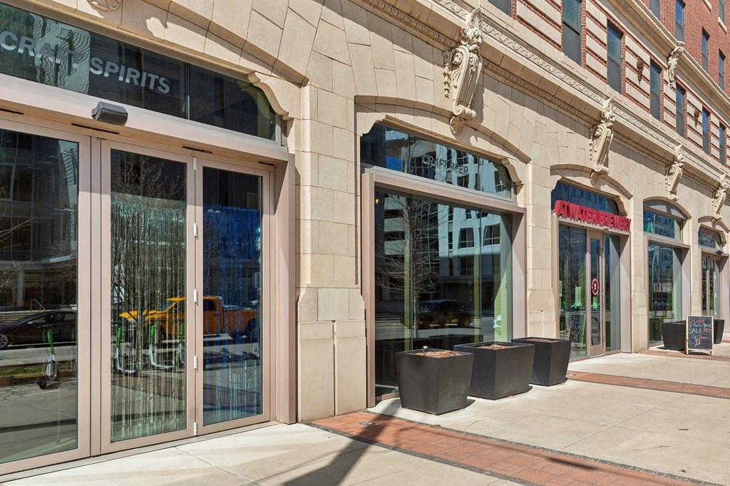the facade of a building with large glass doors and a sidewalk at The Rowe, Grand Rapids, 49503