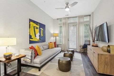 a living room with a gray couch and a yellow painting