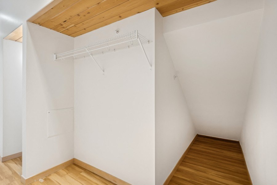 A white room with a wooden ceiling and a white wall with a white door.