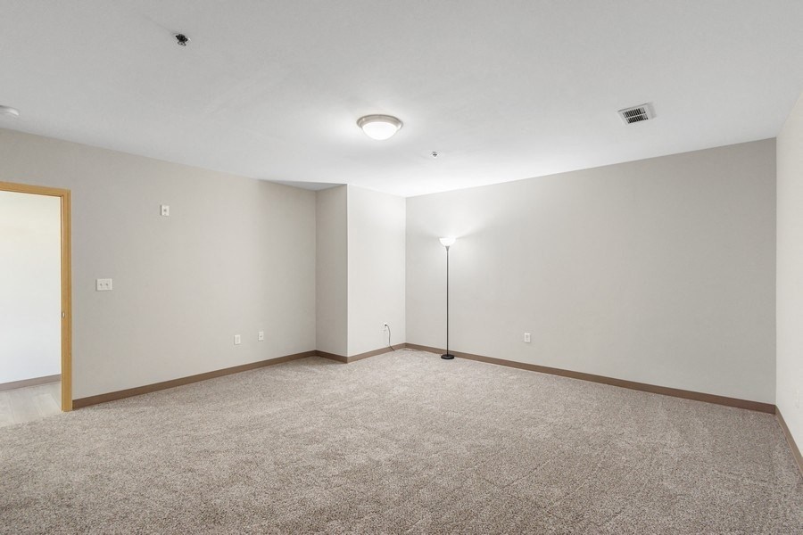 the living room of an empty apartment with carpet and a lamp