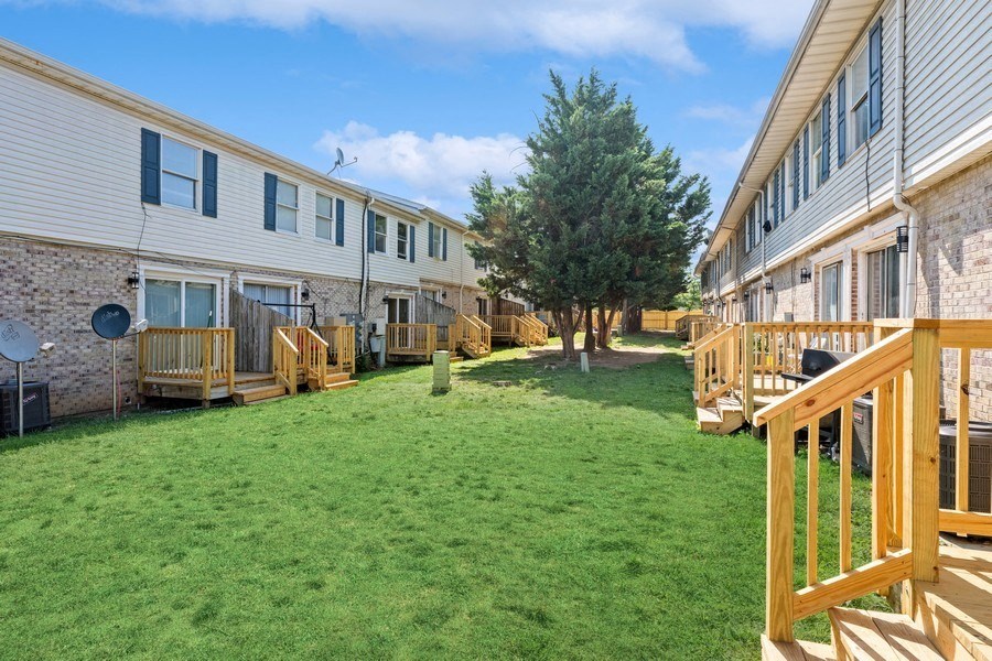 a backyard with green grass and a brick building with a tree in the middle at Fort Collier Terrace, Winchester, VA 22601