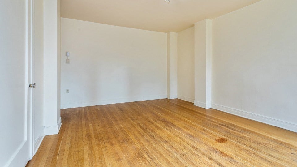 an empty room with wooden floors and white walls