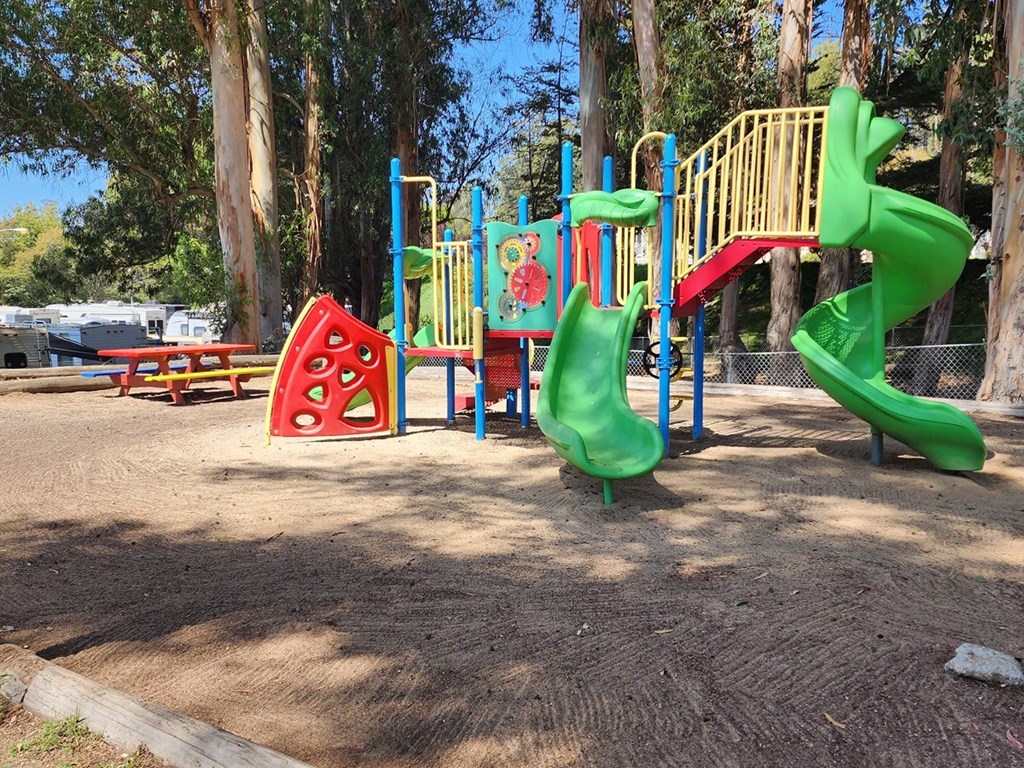 A playground with a green slide and a red and yellow climbing structure at Salinas Sunset Apartments, Salinas, CA