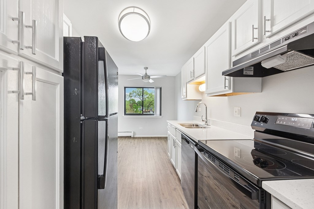 A modern kitchen with black appliances and white cabinets.