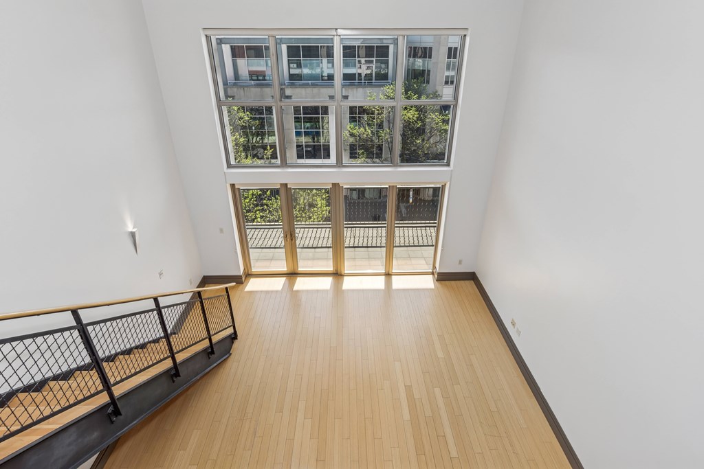 A room with a balcony and a window overlooking a building.