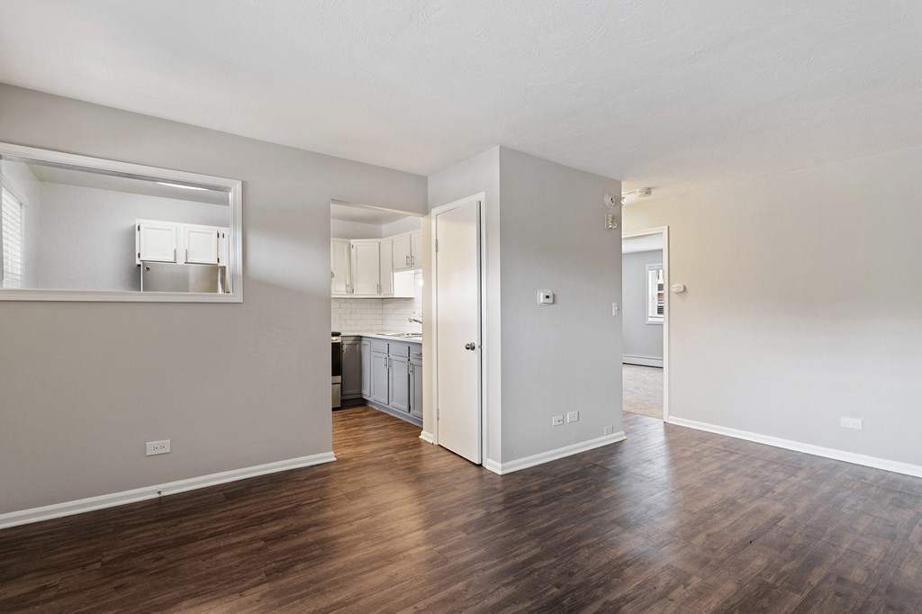 a bedroom with a medium hardwood floor and a kitchen in the background at The Hinsdale, Hinsdale