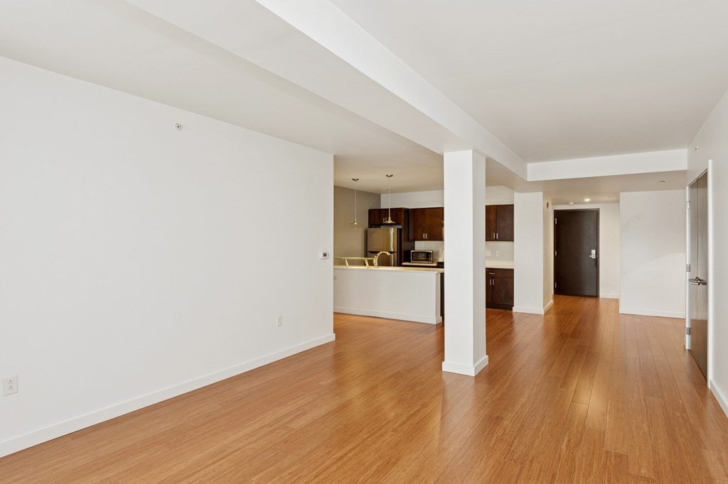 A spacious room with wooden floors and white walls.