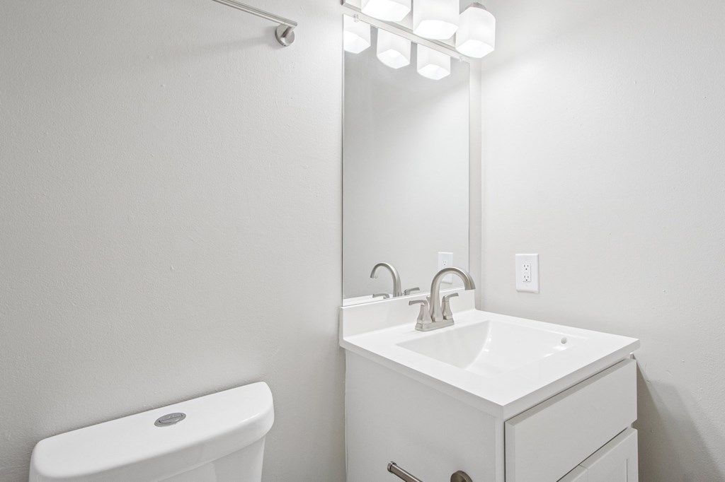 A white bathroom with a sink, toilet and mirror.
