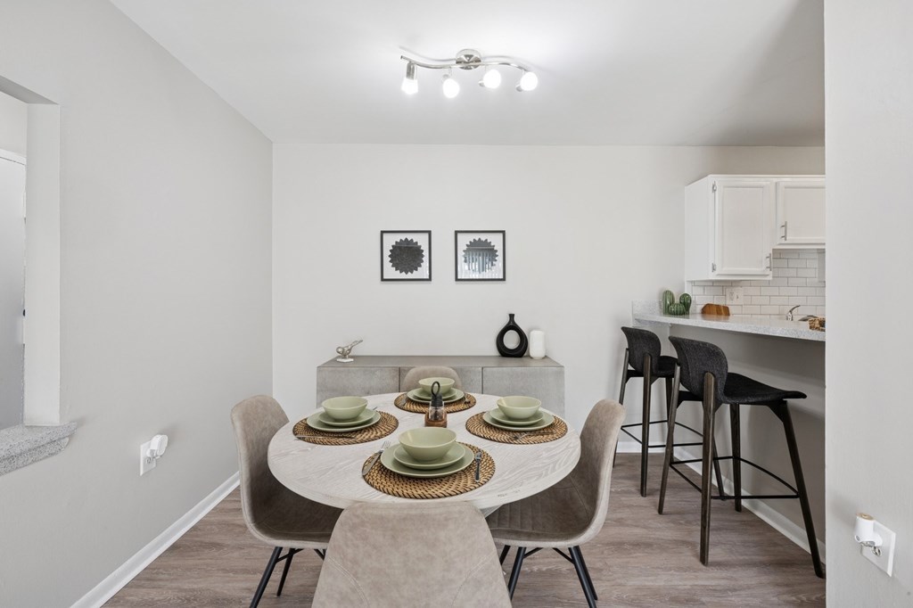 A dining room with a table set for two and chairs around it.