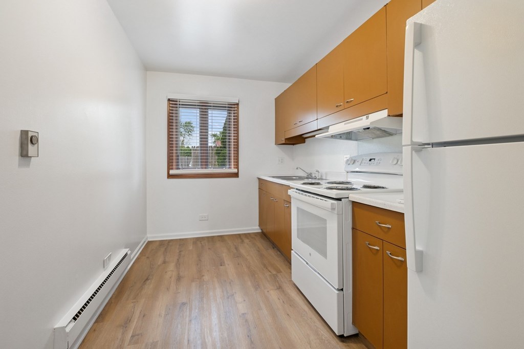 A kitchen with white appliances and wooden cabinets.