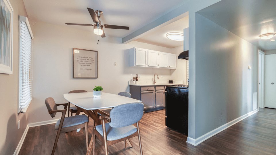 a dining area with a table and chairs and a kitchen in the background at The View Apartments St Charles, St Charles, 60174