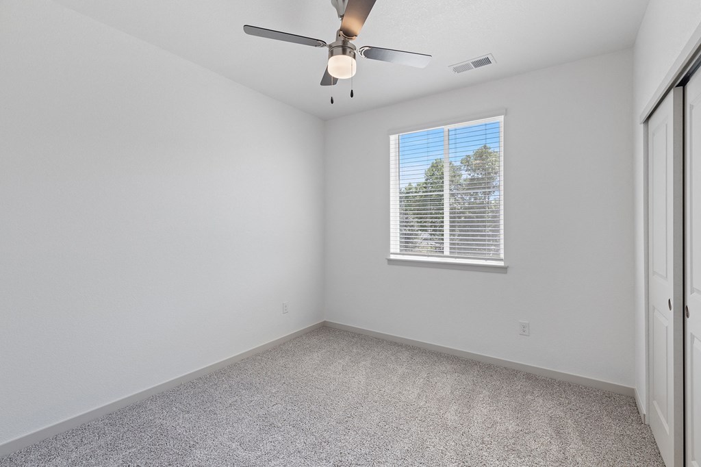an empty room with a ceiling fan and a window