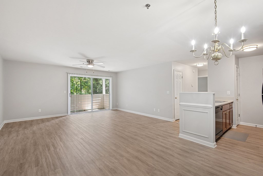 A room with a wooden floor, a ceiling fan, and a chandelier.