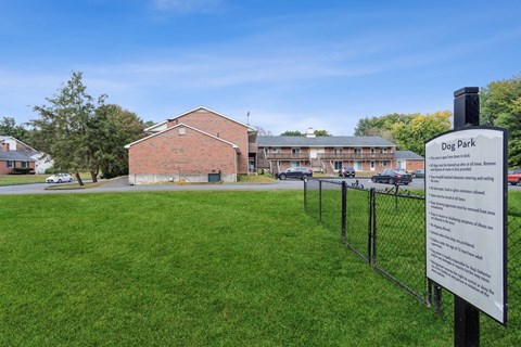 a dog park with a fence and the apartment building in the background at Stonebridge, Ellington, CT, 06029