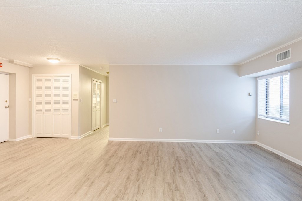 A spacious living room with wooden flooring and white walls