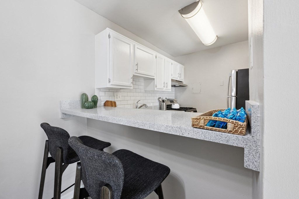 A kitchen with white cabinets and a counter with a basket of blue cloths on it.
