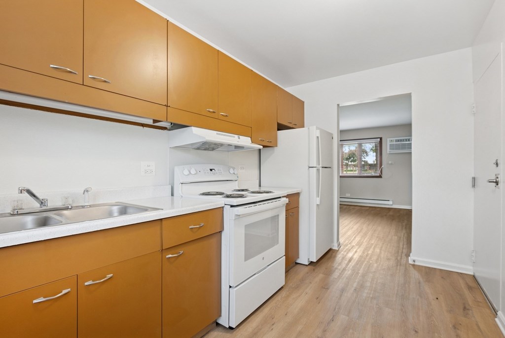 A kitchen with white appliances and wooden cabinets.