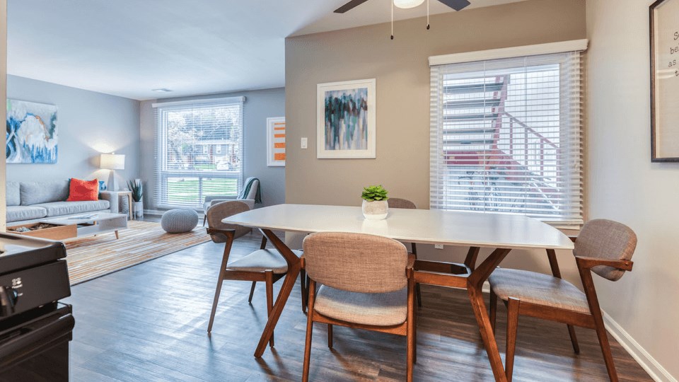 a dining area with a table and chairs and a living room in the background at The View Apartments St Charles, St Charles, IL, 60174