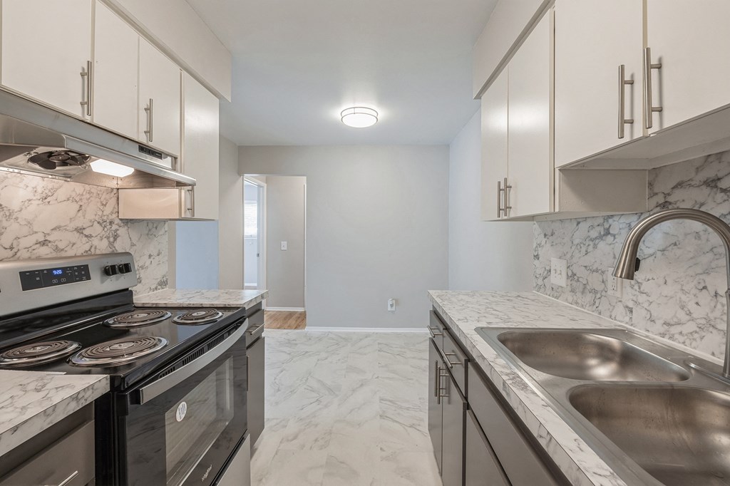 an empty kitchen with marble counter tops and stainless steel appliances