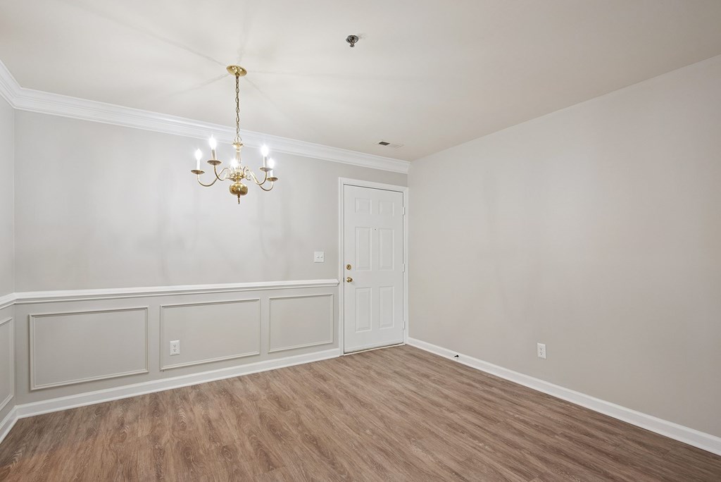 A room with a chandelier, a door, and a wall with paneling.