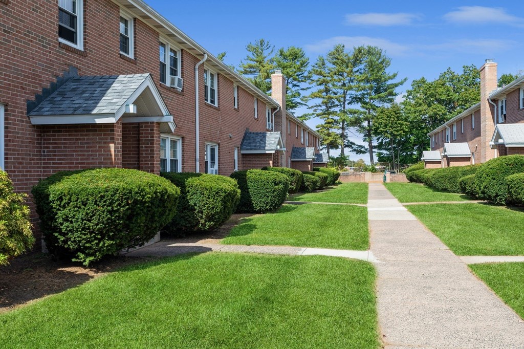 a sidewalk in front of a row of brick apartment building