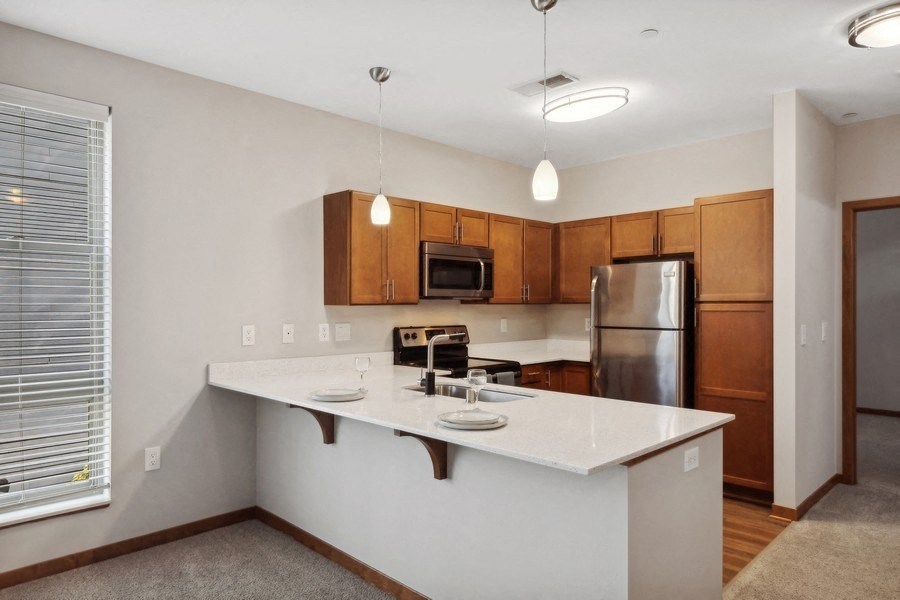 the view of a kitchen with a large island and a stainless steel refrigerator