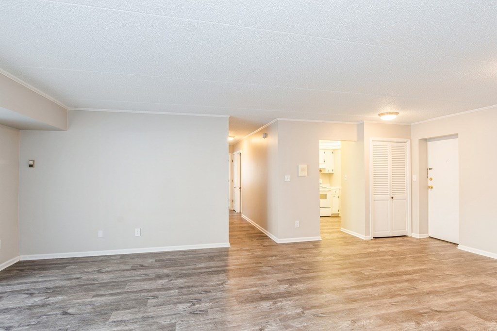 A spacious room with wooden flooring and white walls.