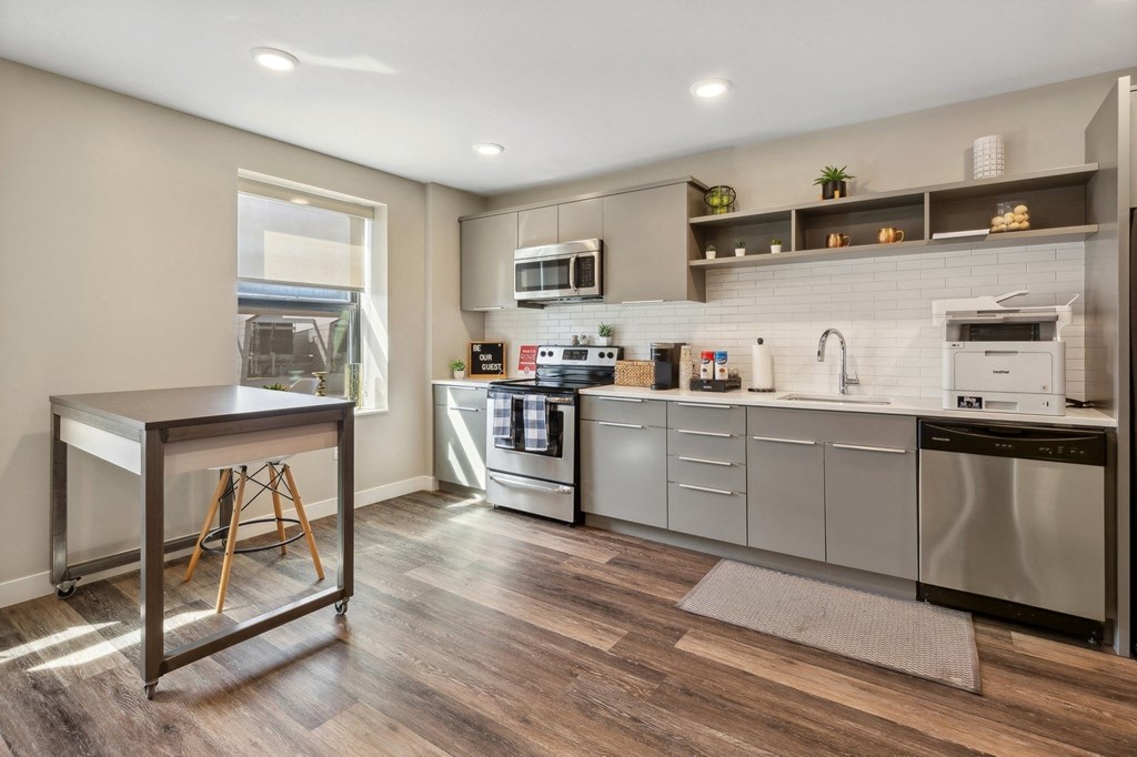 an open kitchen with stainless steel appliances and a table at The Rowe, Grand Rapids, 49503