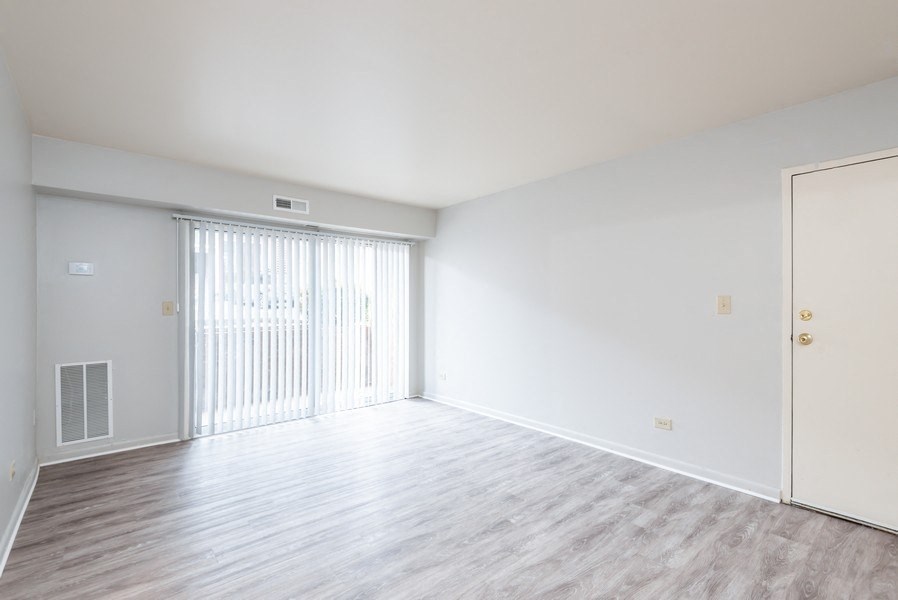 A large, empty room with a sliding door and wooden flooring.