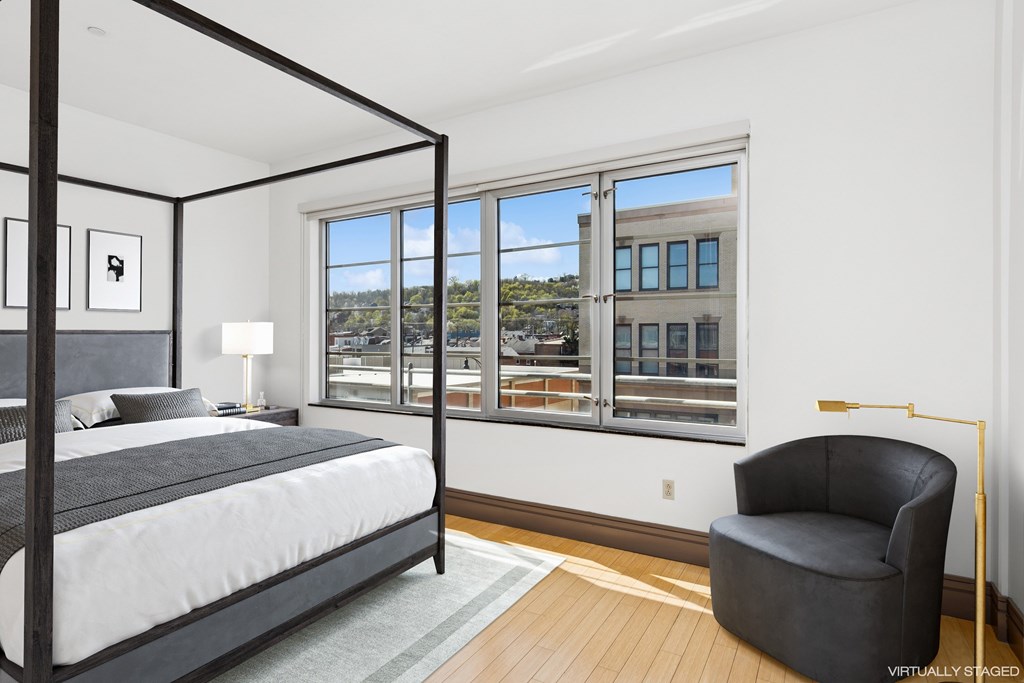 A bedroom with a large bed and a chair.