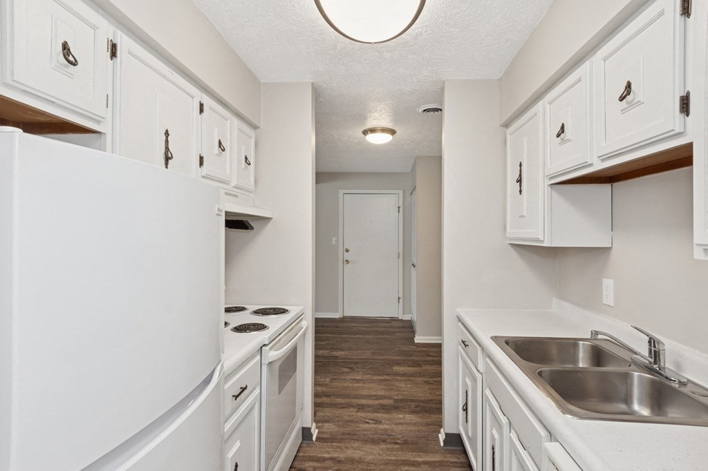 A kitchen with white cabinets and a white refrigerator.