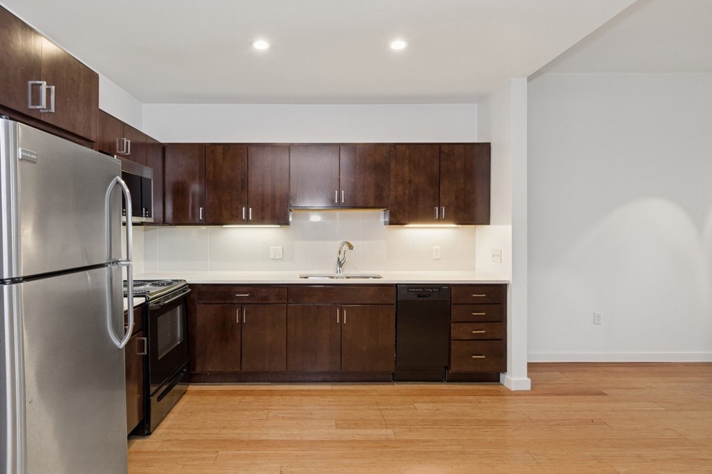 A kitchen with wooden cabinets and a stainless steel refrigerator.