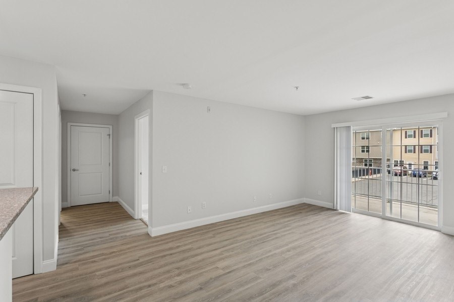 A spacious room with wooden flooring and white walls.