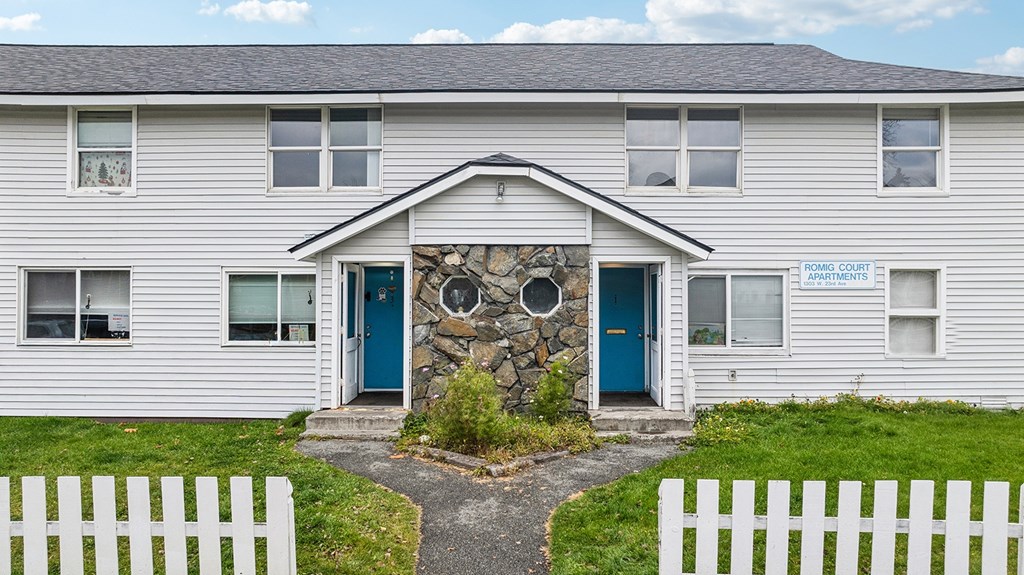 A white building with a blue door and a sign that says