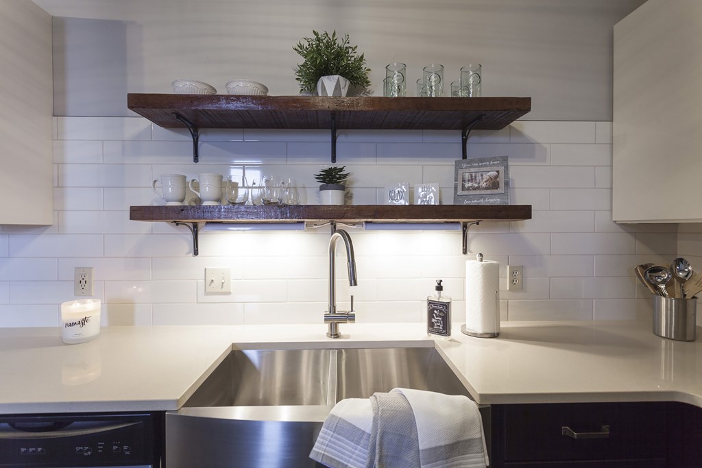 A modern kitchen with a stainless steel sink and white countertop.