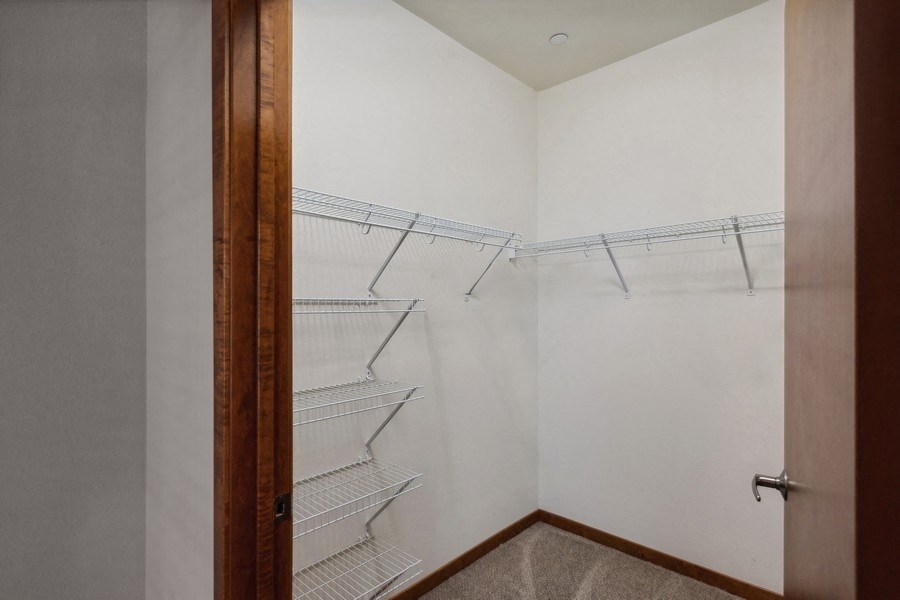 a walk-in closet in the master bedroom with a closet door and shelves