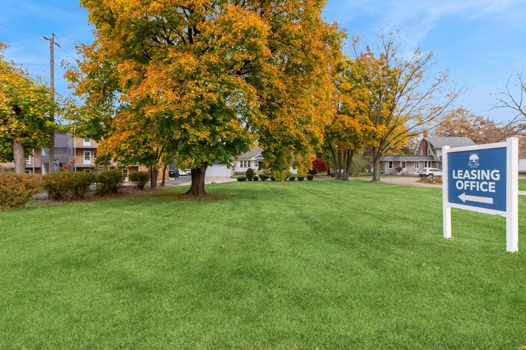 a leasing office sign in the middle of a green lawn at River Oaks, North Aurora