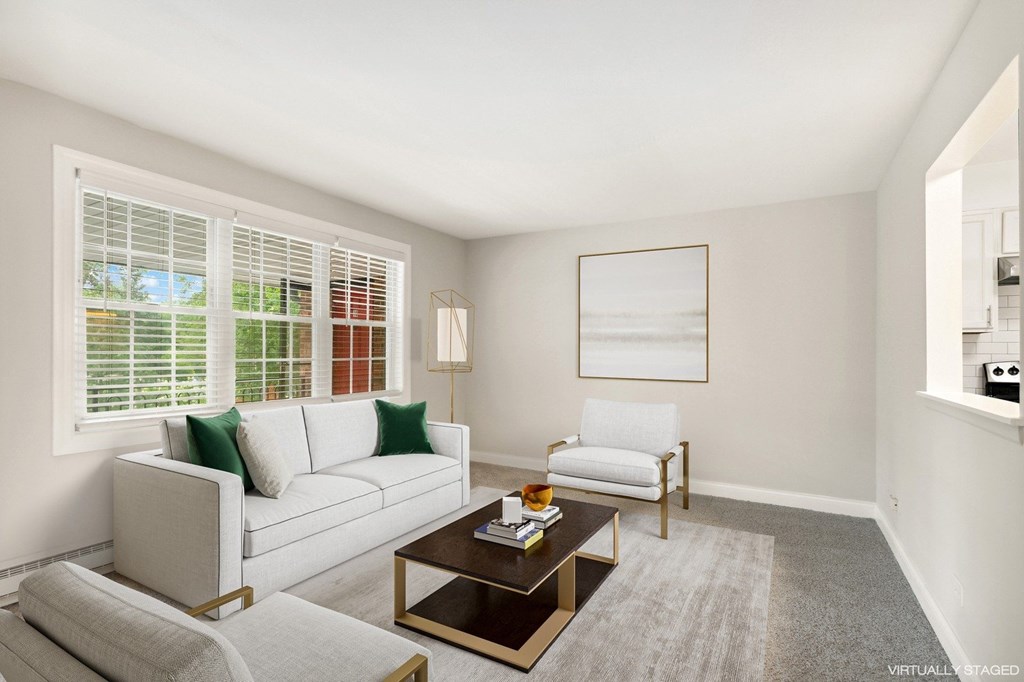 A living room with a white couch, a coffee table, and a window with blinds.
