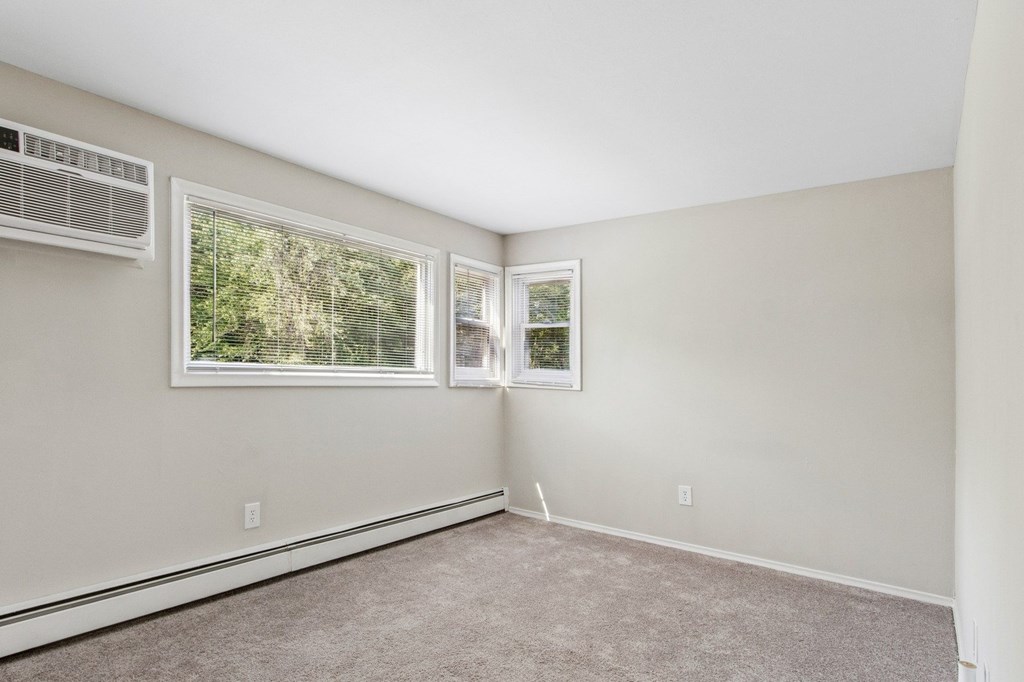 A room with a window and a picture frame on the wall.