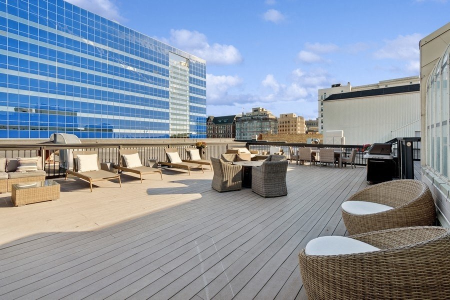 a rooftop deck with chairs and tables on a skyscraper