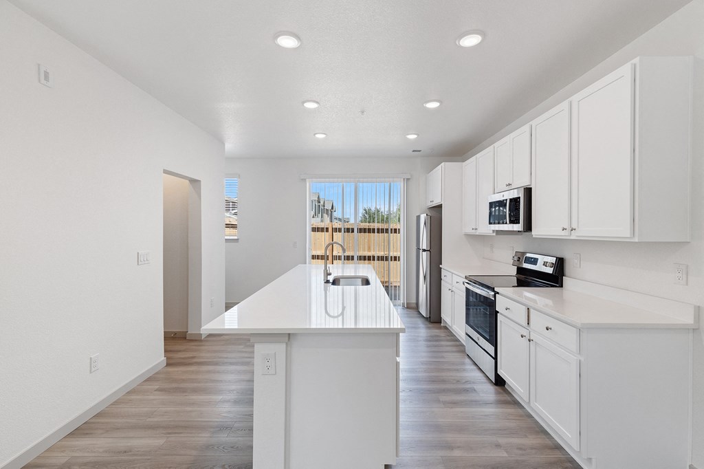 an empty kitchen with white cabinets and a white counter top