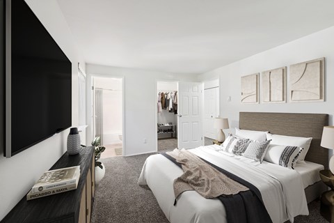 A bedroom with a large bed and a flat screen TV mounted on the wall.