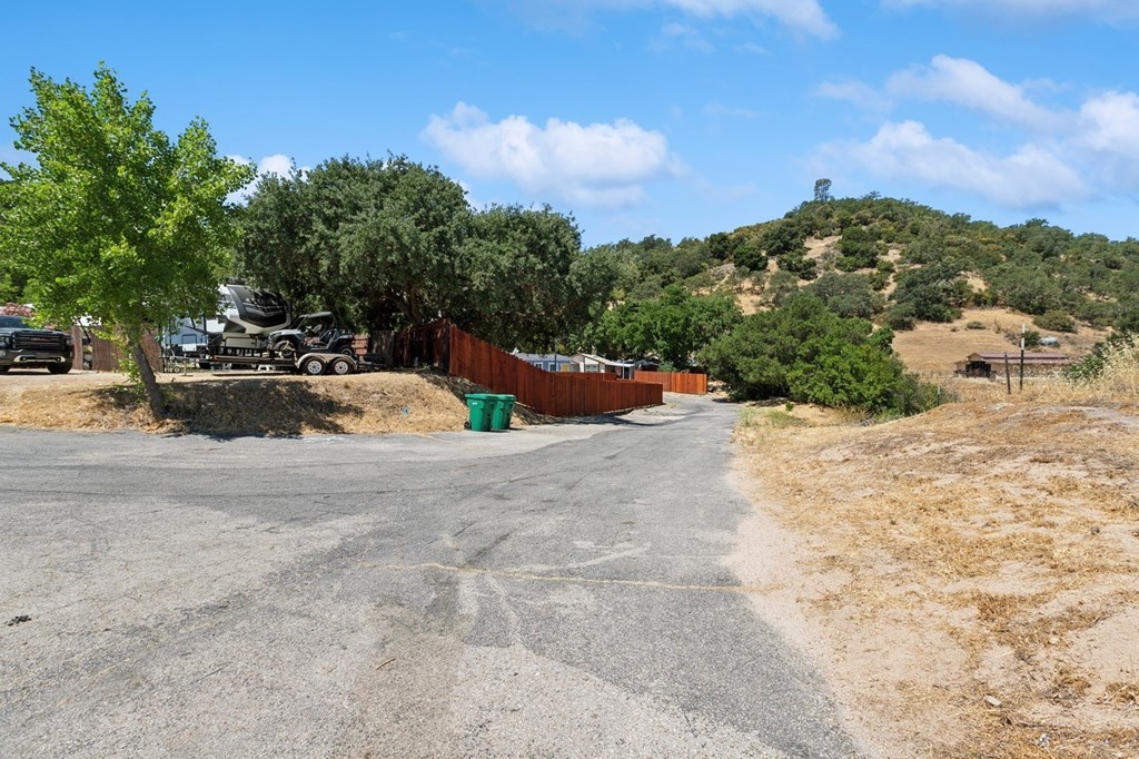 A parking lot with a hill and trees in the background.