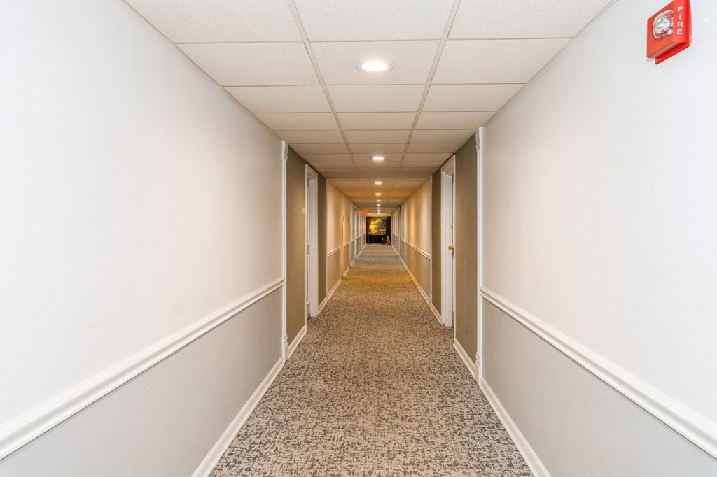 A long hallway with a carpeted floor and white walls.
