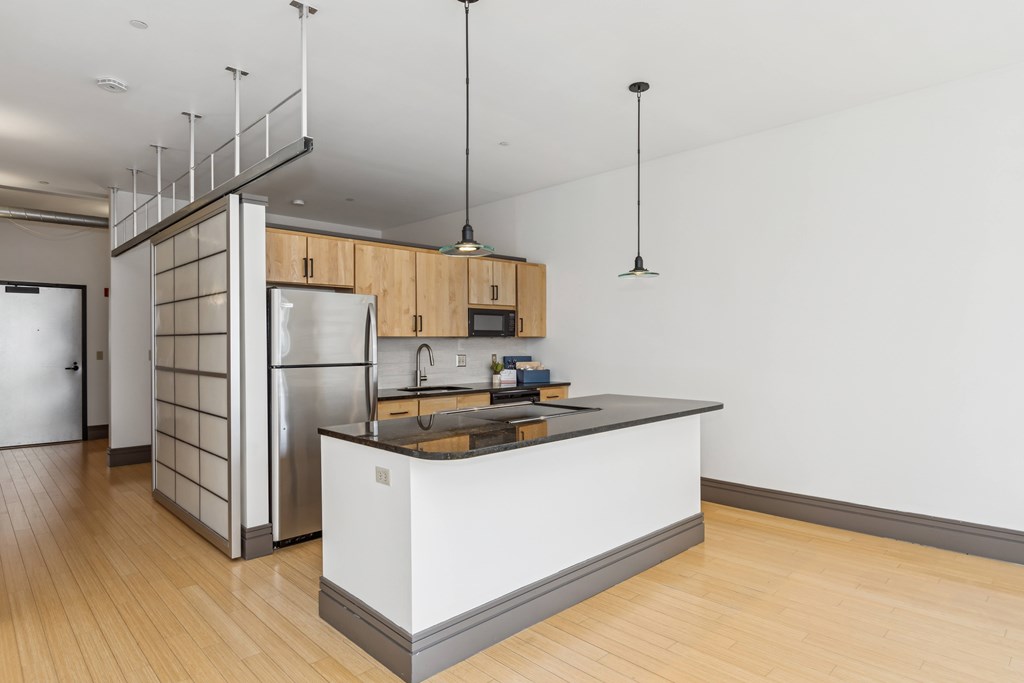 A modern kitchen with wooden floors and a white island.